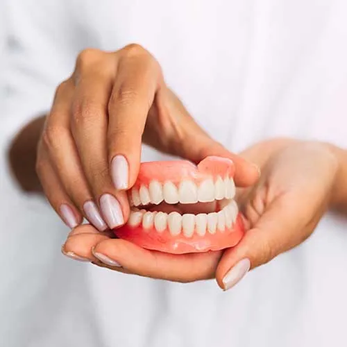 Pair of dentures held by dentist